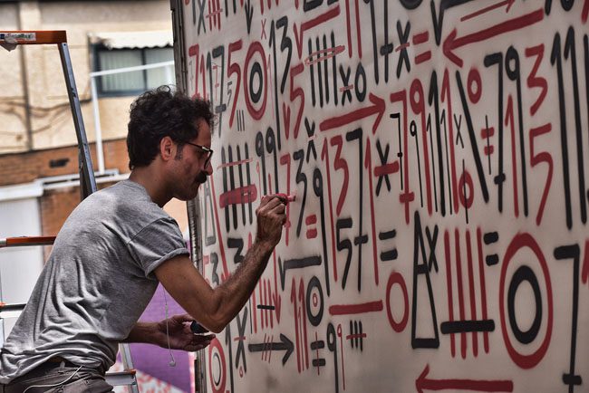 El artista Sixeart trabajando en un graffiti